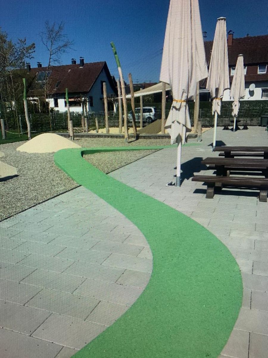 Neu angelegter Spielbereich mit farbigem Belag und Pflasterweg
